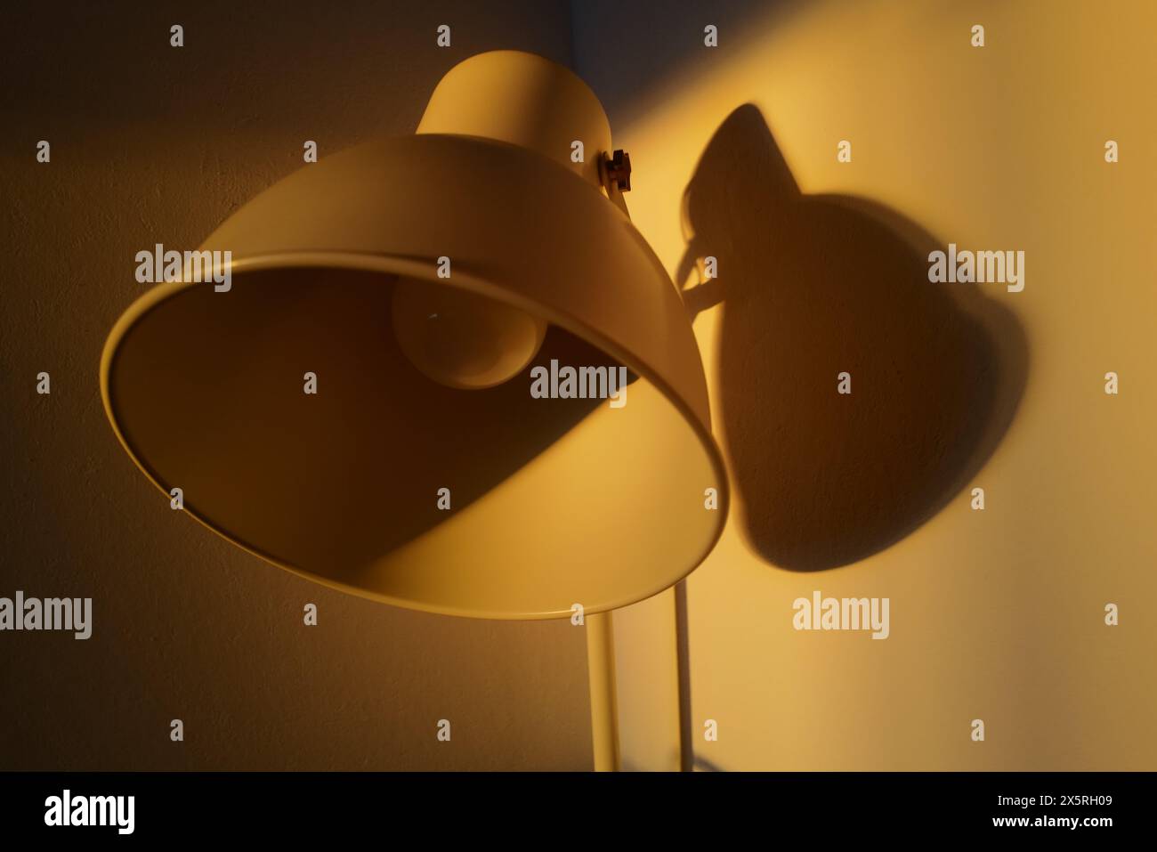 Cattura l'essenza della tranquillità e della semplicità, questa composizione minimalista presenta una lampada in metallo bianco inondata di luce serale Foto Stock
