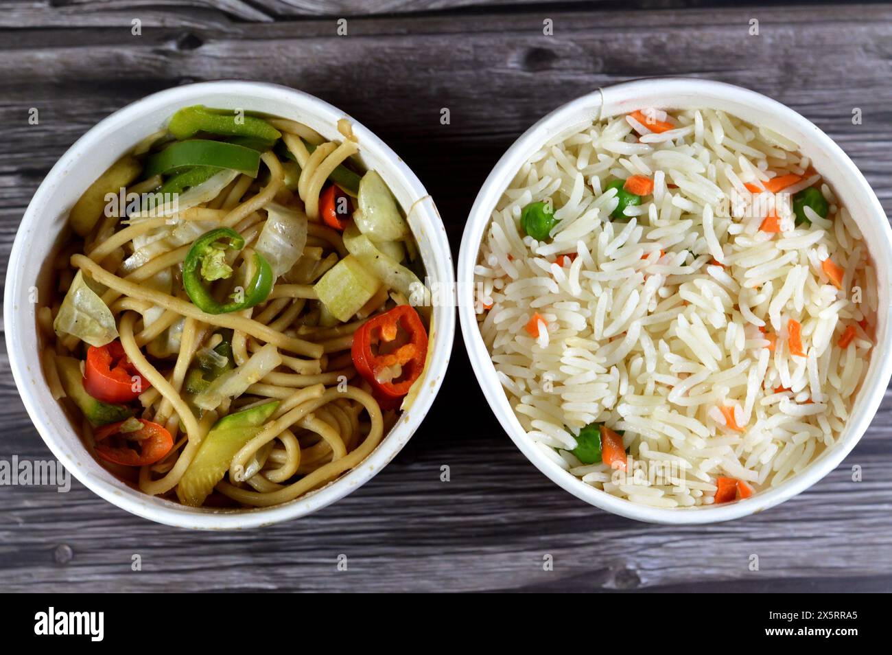 Spaghetti e riso sulla cucina asiatica, cibo cinese, riso basmati bianco a grani lunghi con verdure, carote e piselli e spaghetti cinesi con cipolle e così via Foto Stock