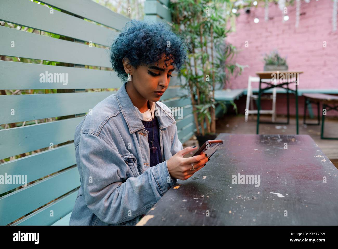 Giovane donna con i capelli blu che usa il telefono Foto Stock