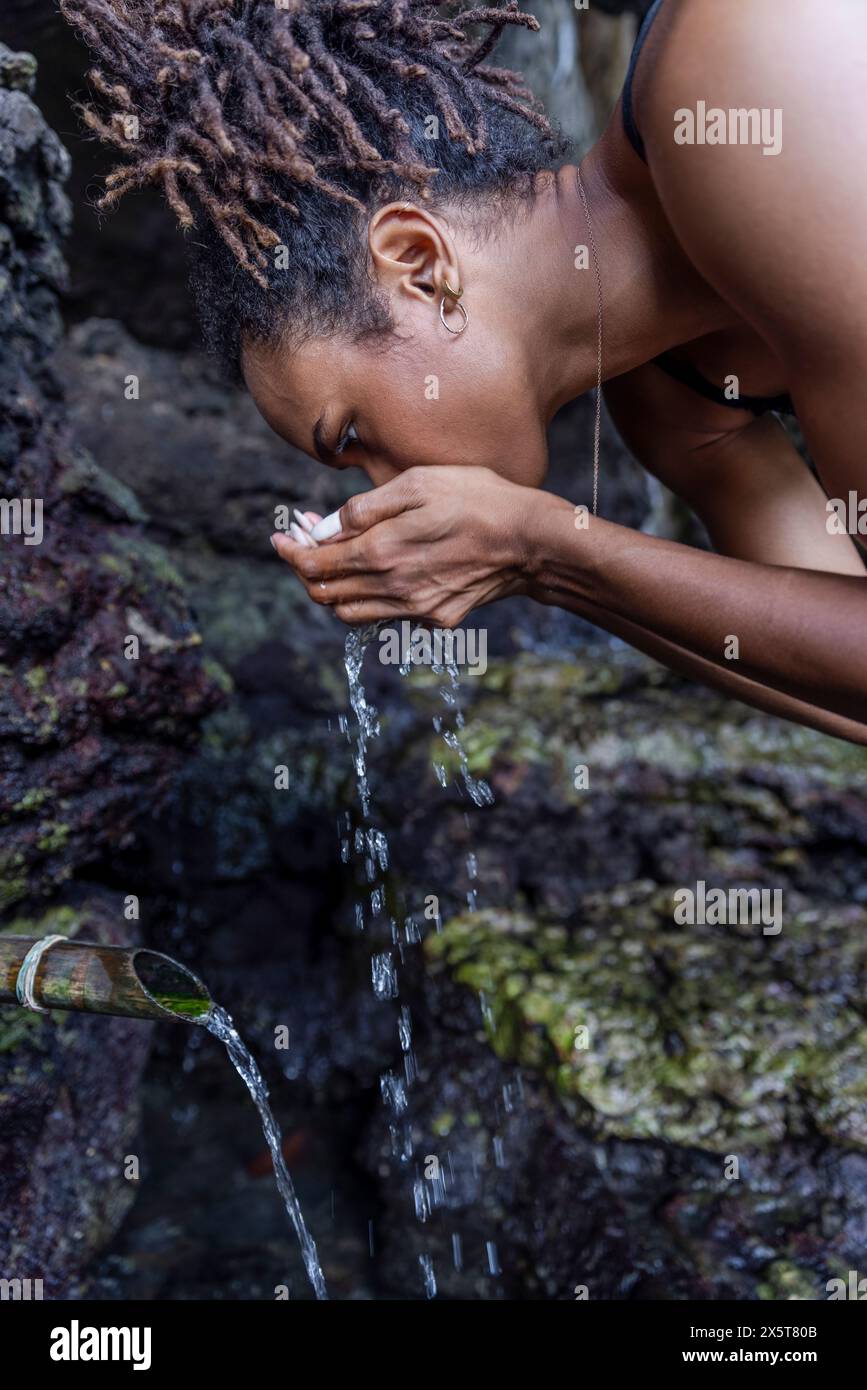 Donna che beve acqua naturale dalla sorgente Foto Stock