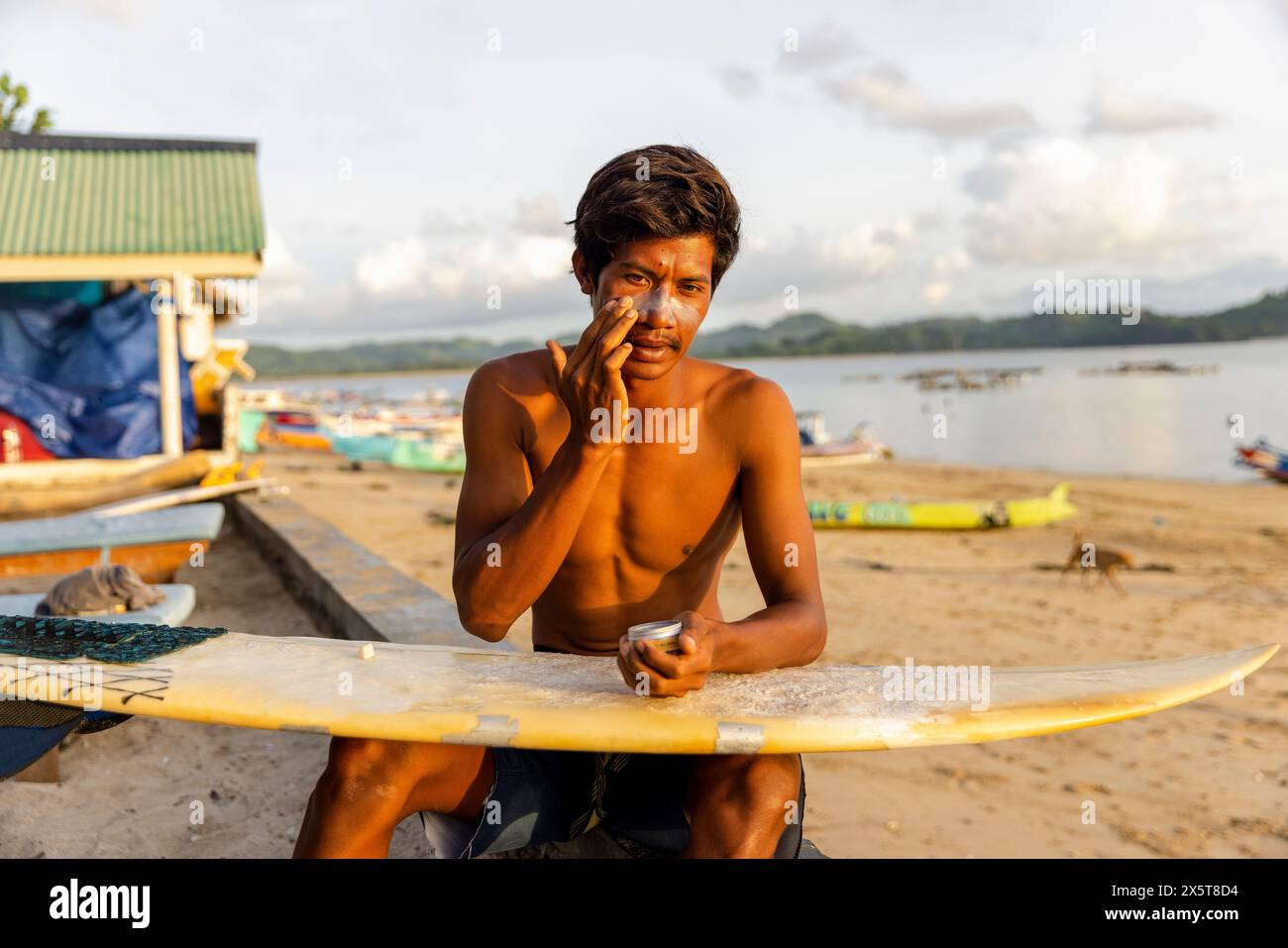 Indonesia, Lombok, surfista maschile che applica lozione solare sul viso Foto Stock