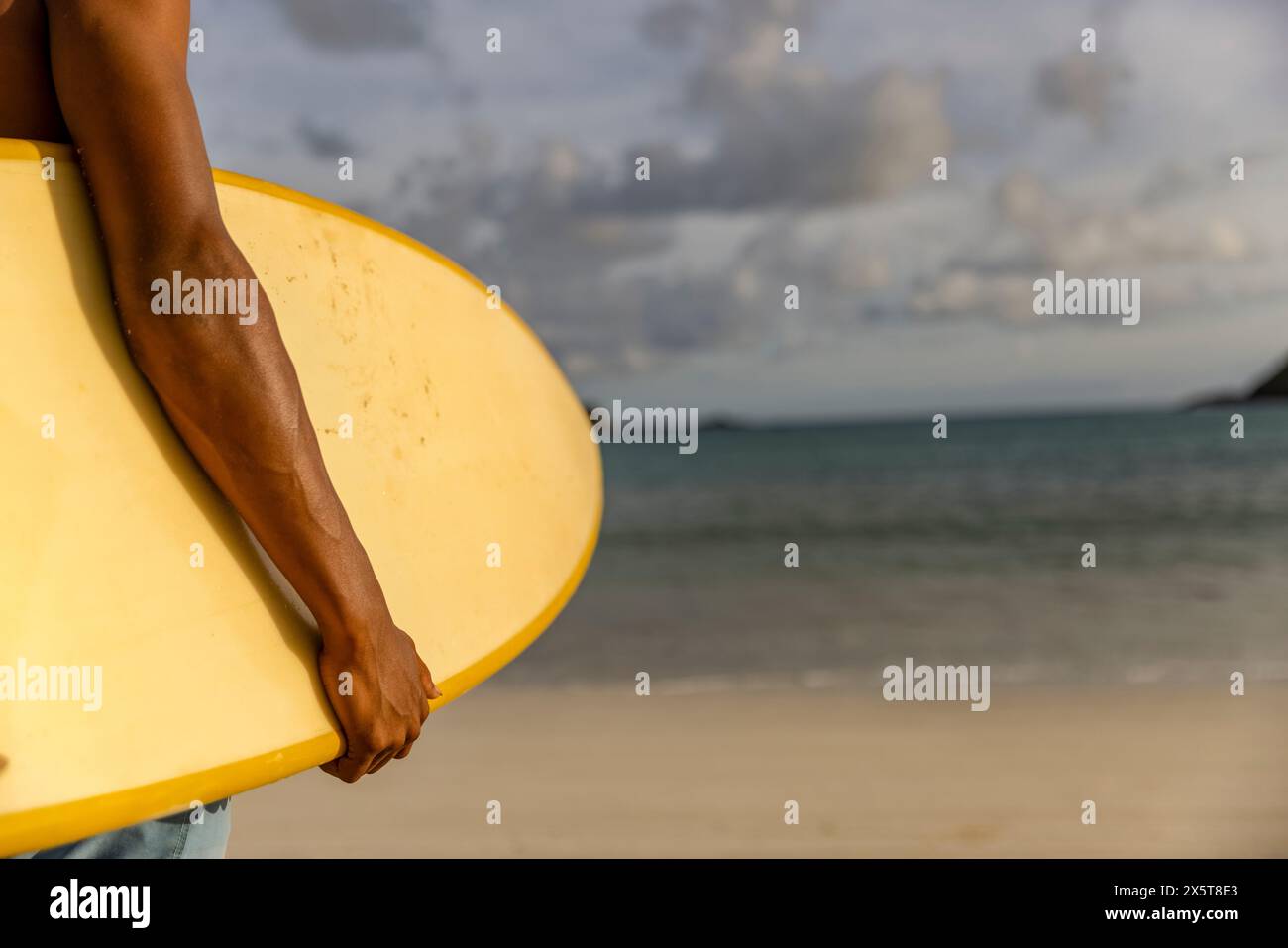 Surfer tenendo la tavola da surf in spiaggia Foto Stock