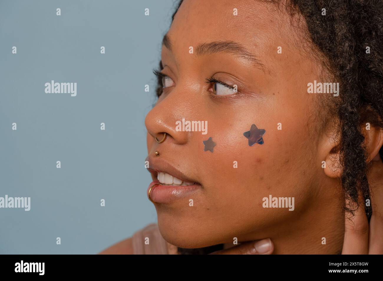 Primo piano di una giovane donna che indossa adesivi stellari sul viso Foto Stock