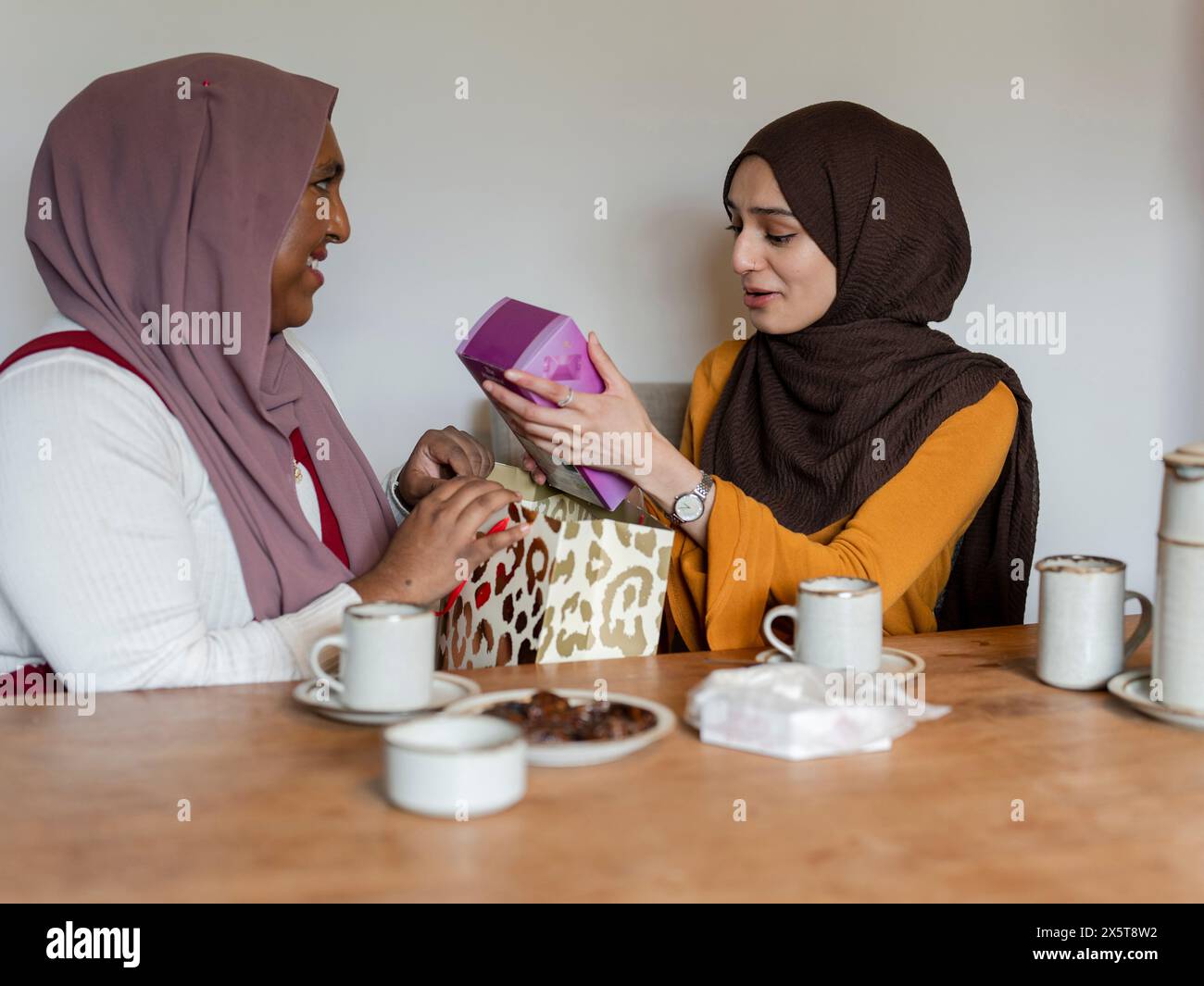 Donna che rimuove il regalo a casa Foto Stock