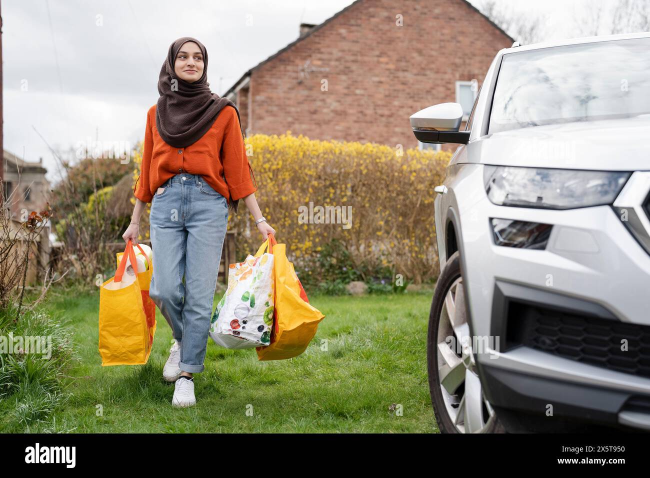 Donna che indossa un hijab che torna a casa con le borse della spesa Foto Stock