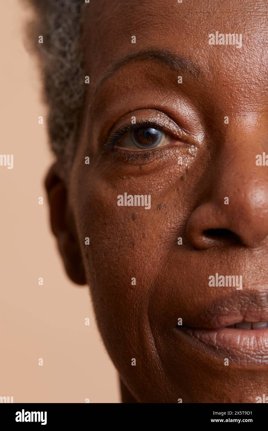 Ritratto ravvicinato di una donna anziana su sfondo beige Foto Stock