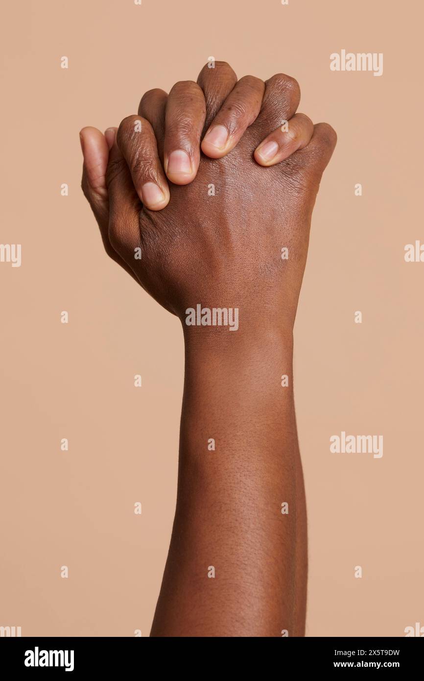 Mani stringute di donna su sfondo beige Foto Stock