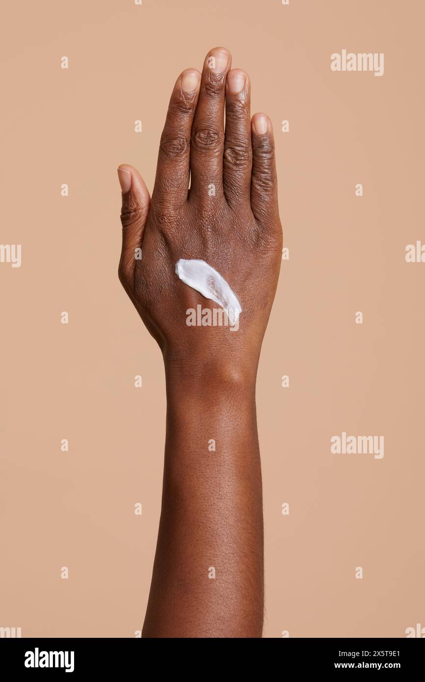 Donna mano con crema su sfondo beige Foto Stock