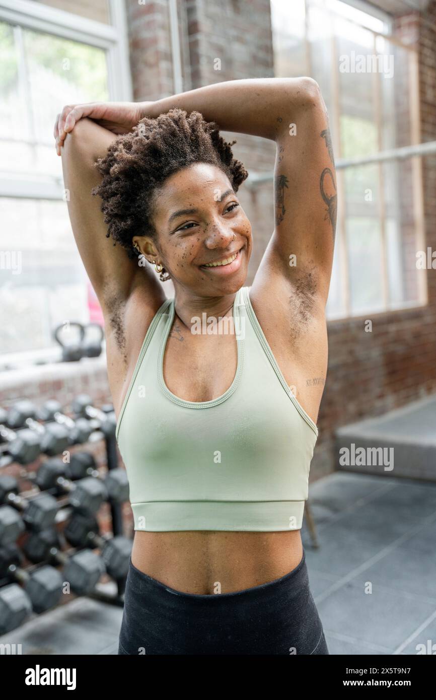 Donna che allunga le braccia in palestra prima di allenarsi Foto Stock