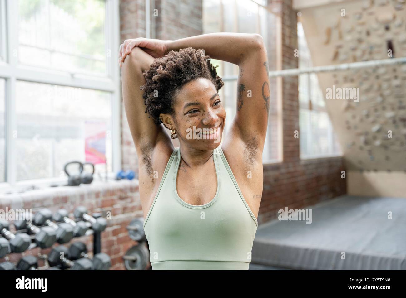 Donna che allunga le braccia in palestra prima di allenarsi Foto Stock