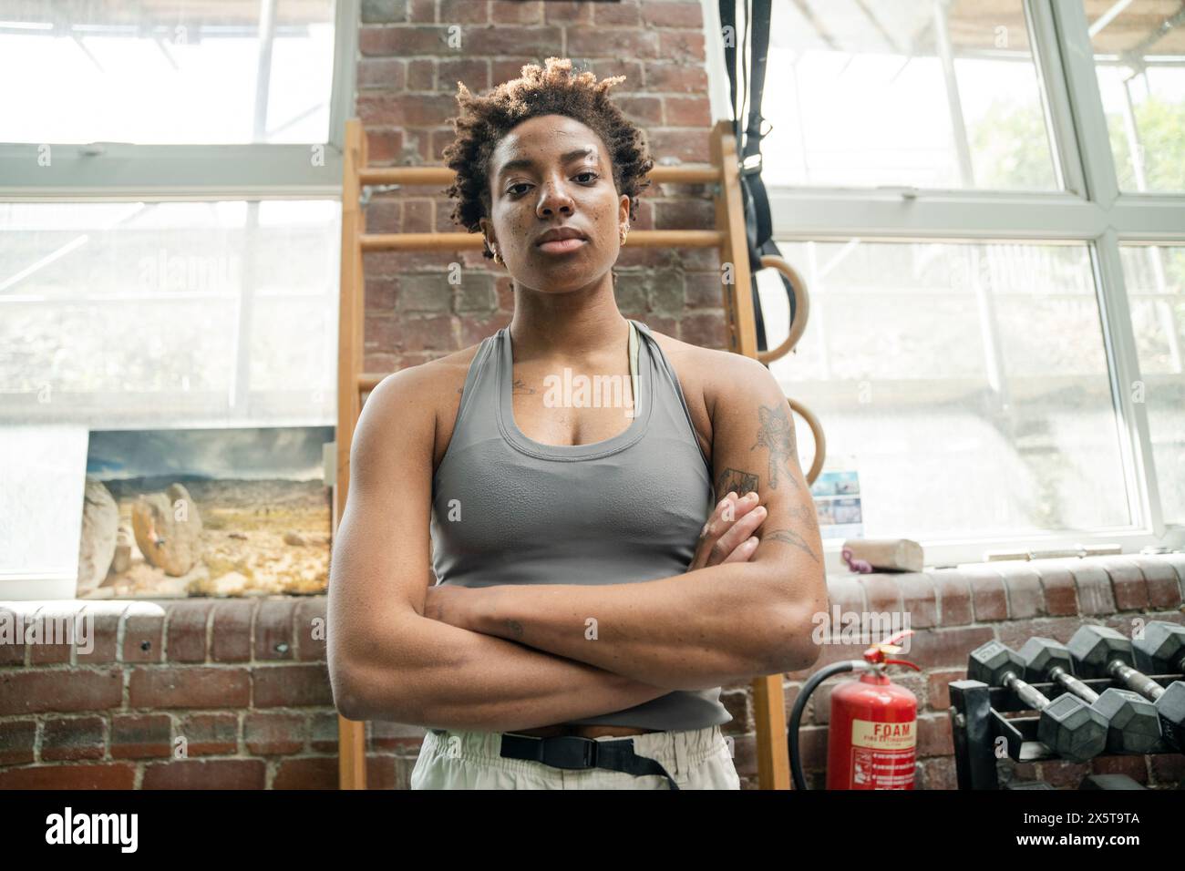 Ritratto di donna seria in piedi con le braccia incrociate in palestra Foto Stock