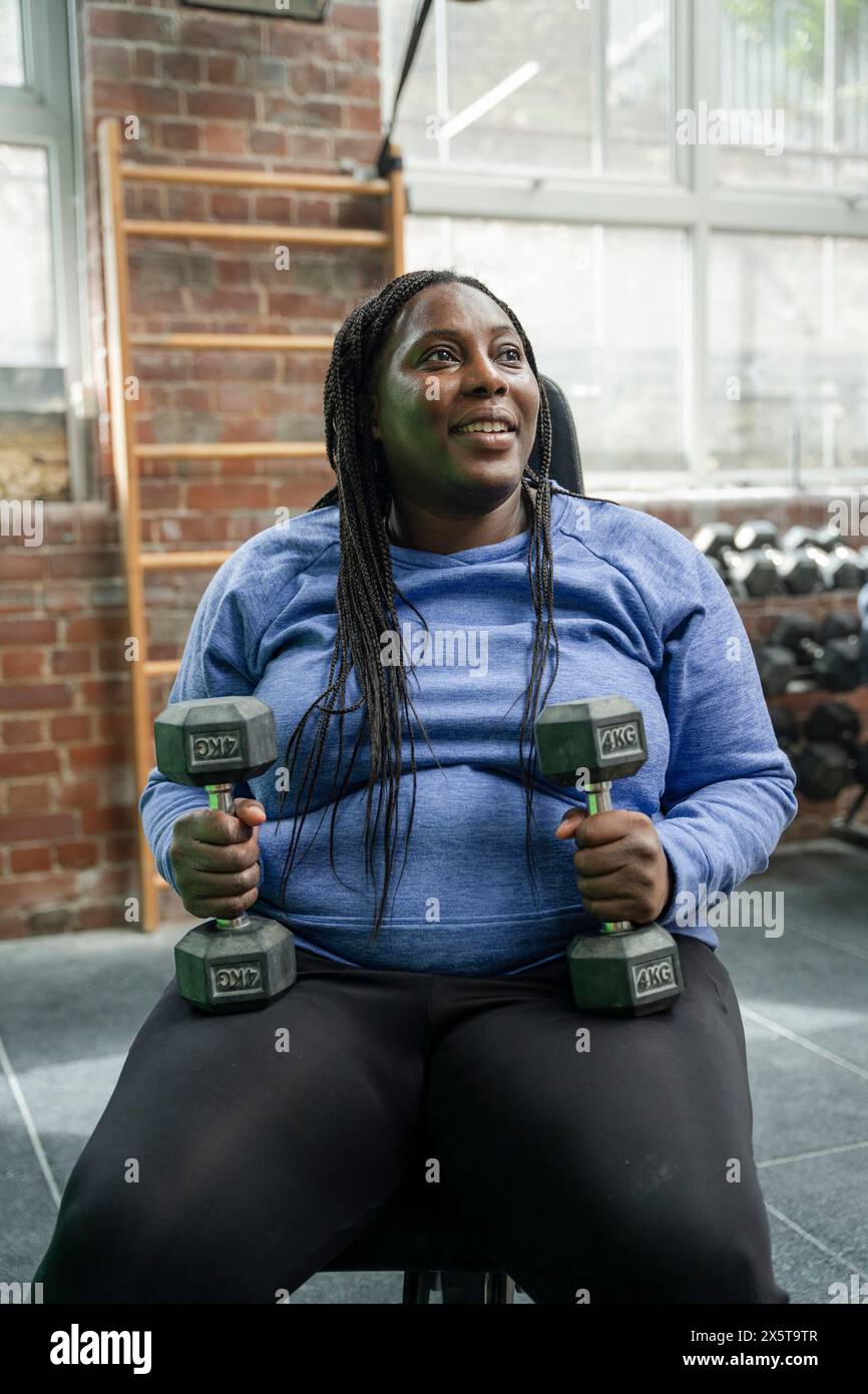 Donna esercizio con manubri in palestra Foto Stock