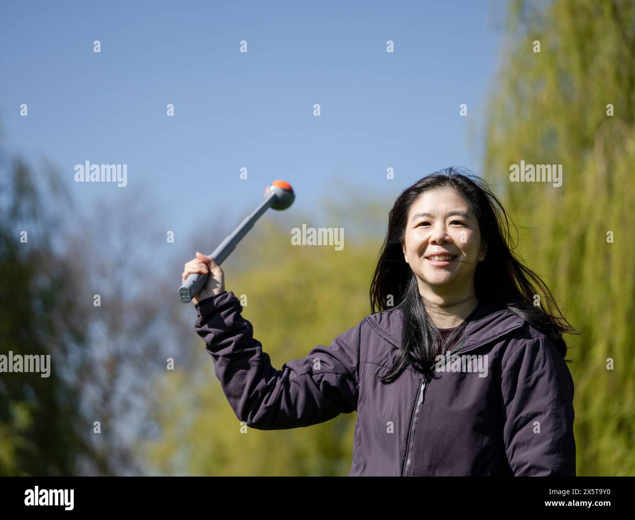 Donna sorridente che tiene in mano il giocattolo contro il cielo limpido Foto Stock