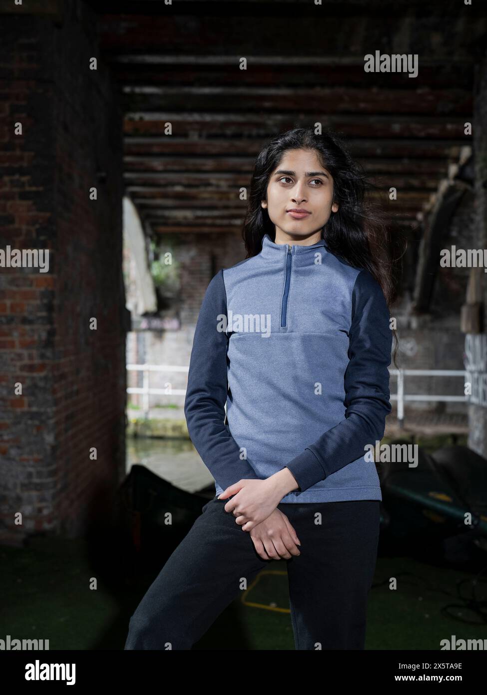 Giovane donna bruna in piedi sotto il ponte vicino al canale Foto Stock