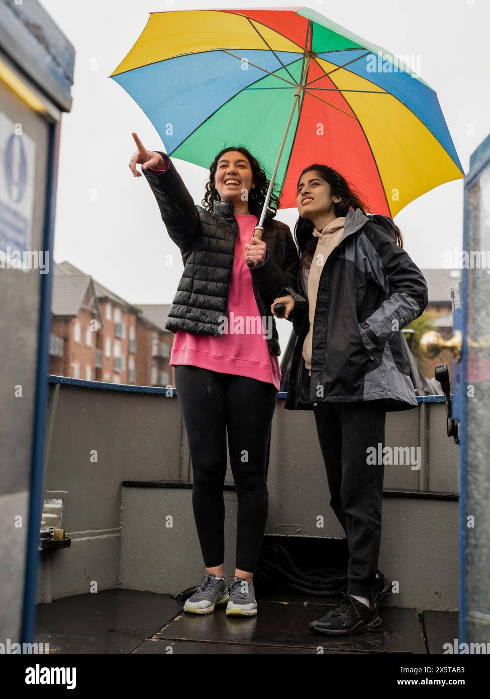 Giovani donne che guardano la vista dalla barca durante la pioggia Foto Stock