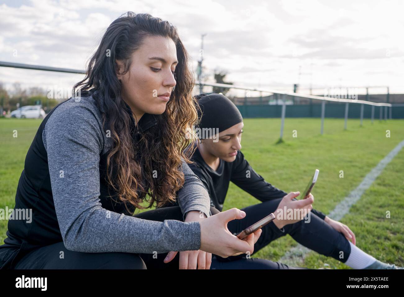 Giocatrici di calcio femminili che usano i telefoni durante le pause Foto Stock