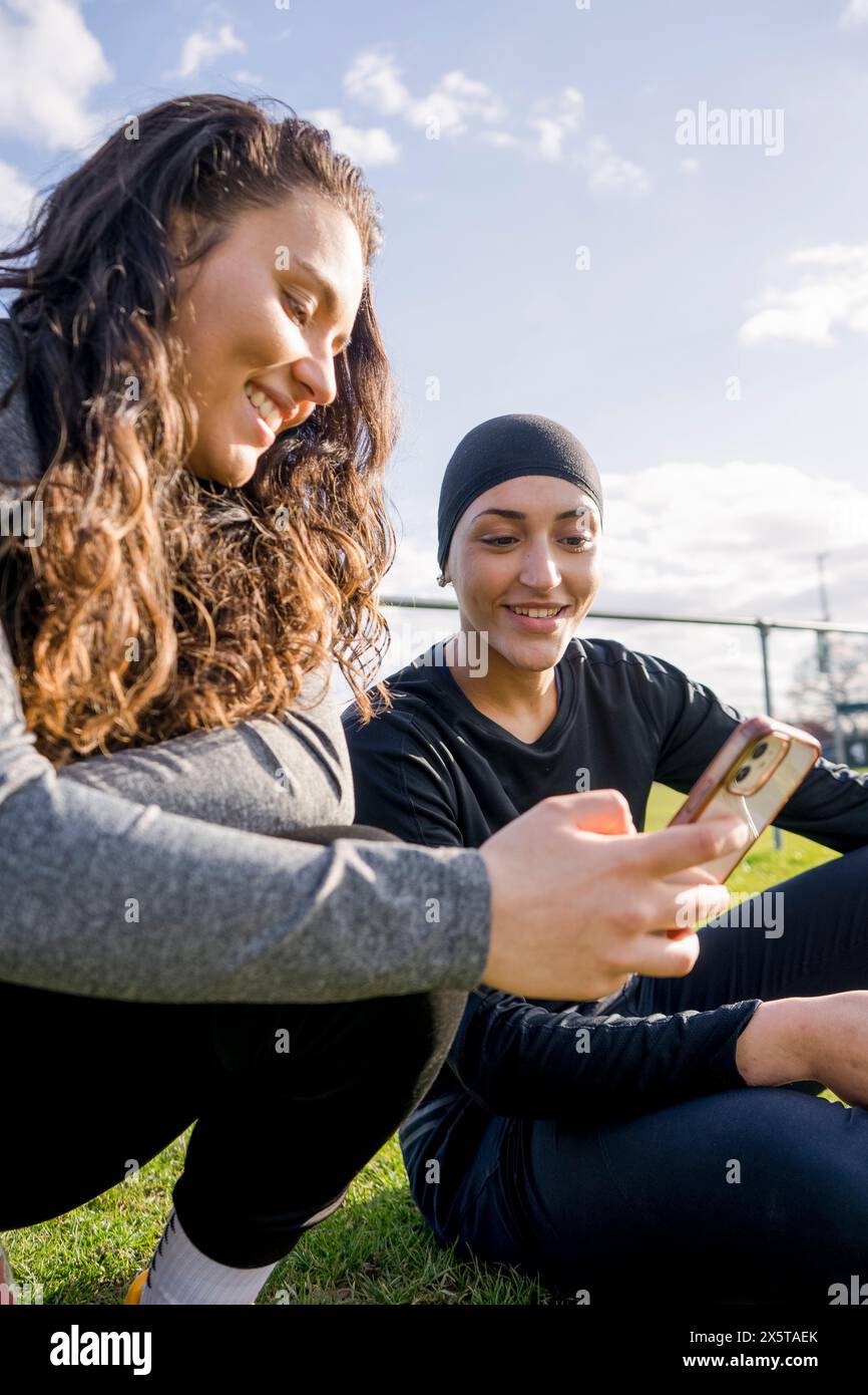 Giocatrici di calcio femminili che usano il telefono durante le pause Foto Stock