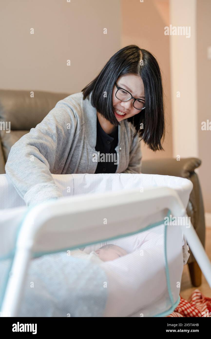 Madre che guarda il bambino (0-1 mesi) in culla Foto Stock