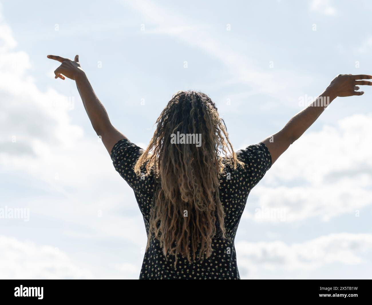 Vista posteriore della donna in piedi con le braccia tese contro il cielo Foto Stock