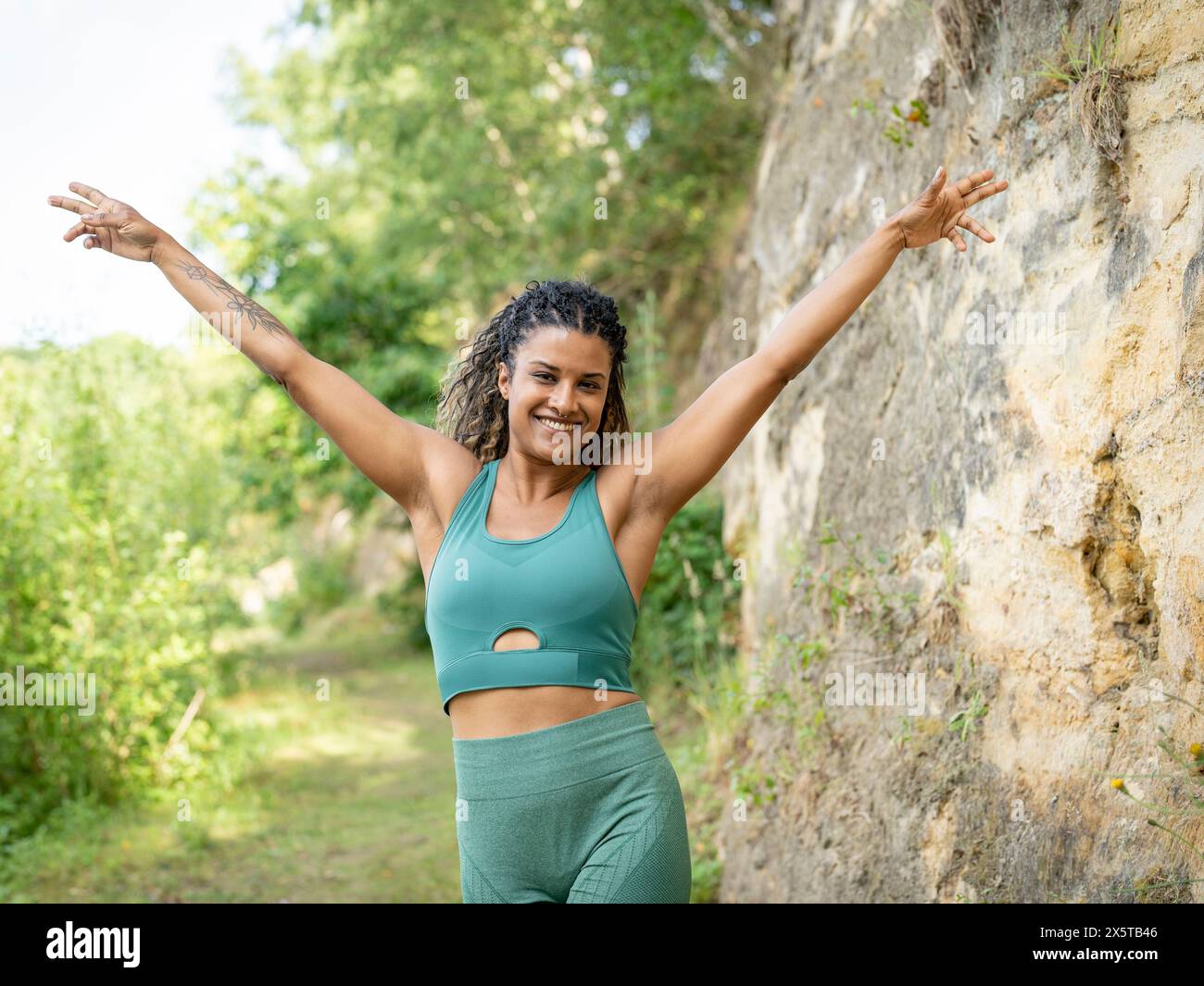 Ritratto di donna sorridente in piedi con le braccia sollevate Foto Stock
