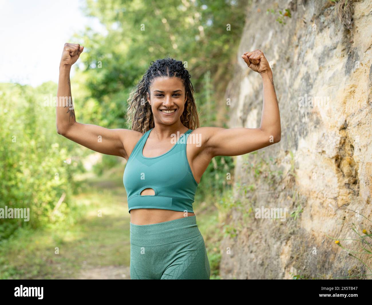 Ritratto di donna sorridente in piedi con le braccia sollevate Foto Stock