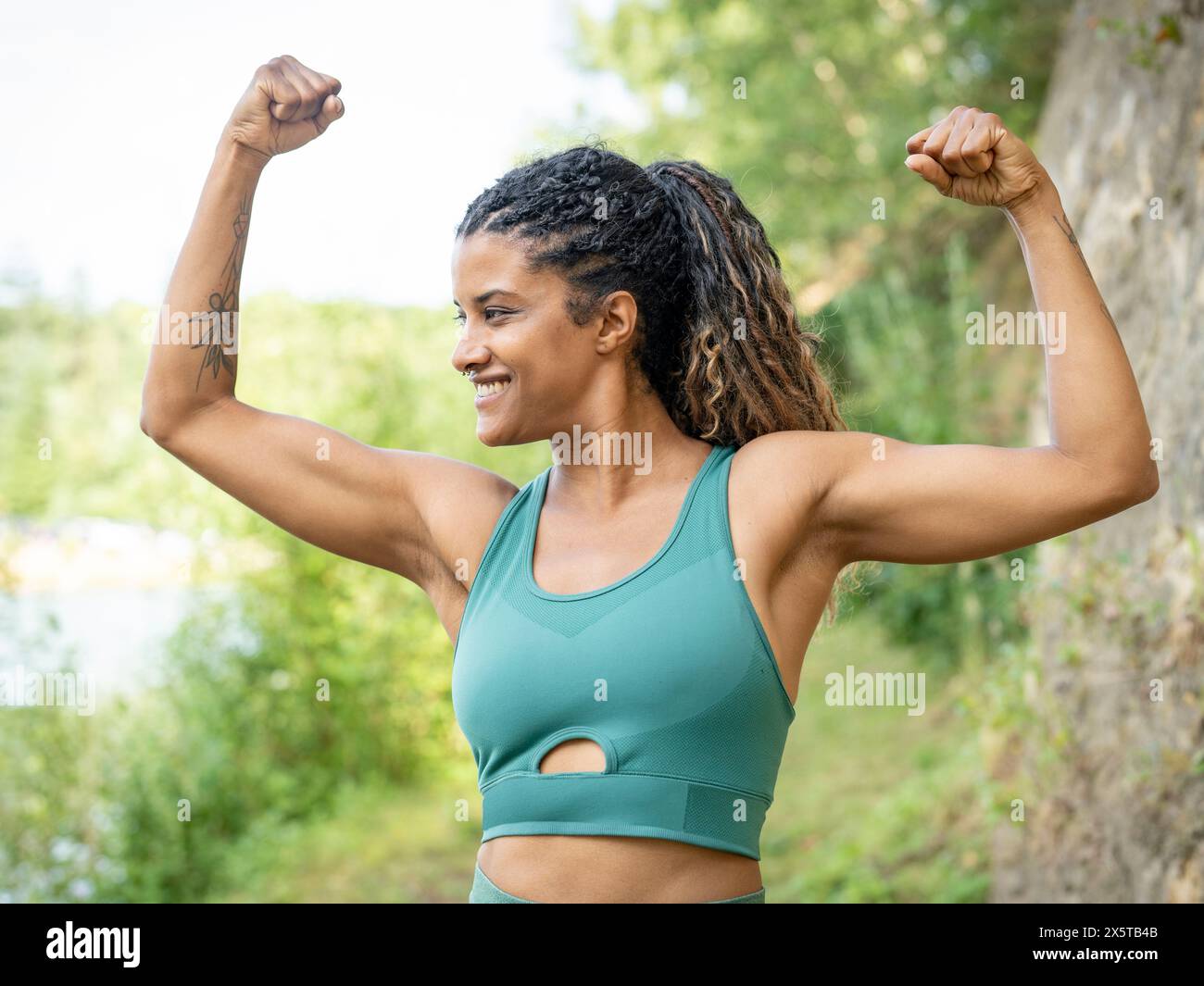 Ritratto di donna sorridente in piedi con le braccia sollevate Foto Stock