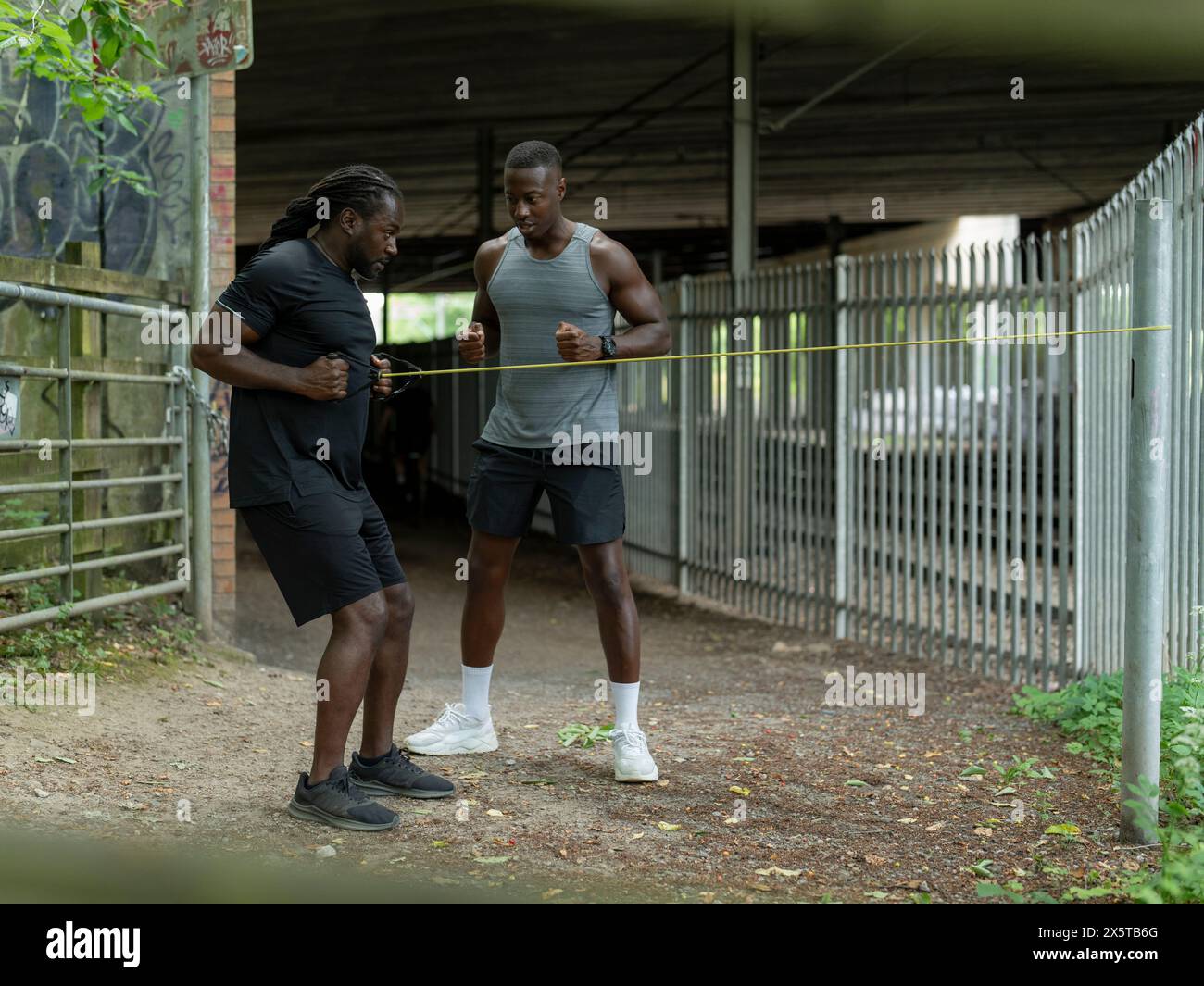 Due uomini che si allenano con la banda di resistenza all'aperto Foto Stock