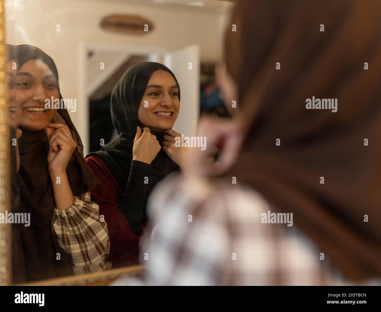 Le donne vestono hijab davanti allo specchio per festeggiare il Ramadan a casa Foto Stock