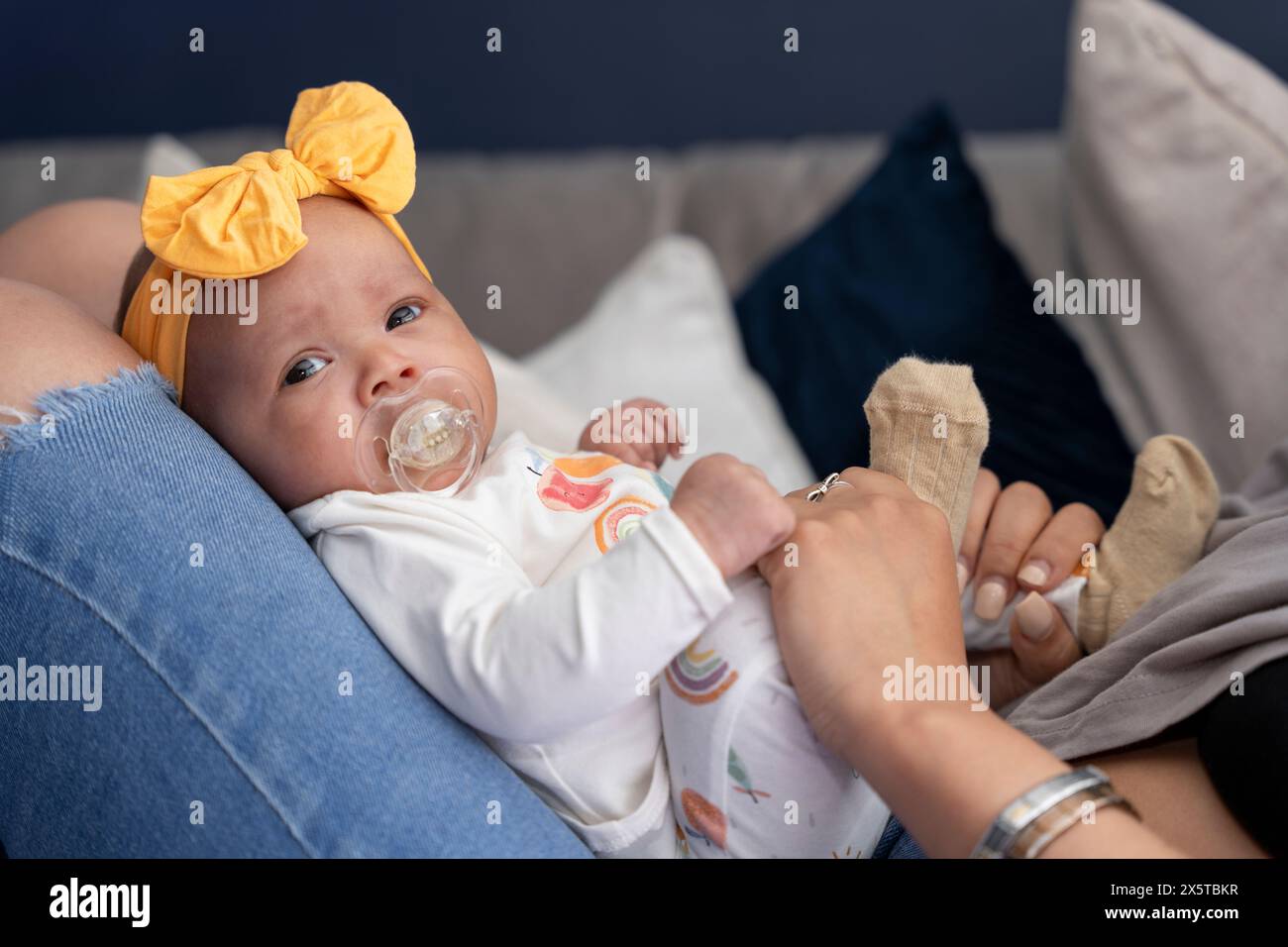 Ritratto di una bambina seduta sulla madre che lambisce a casa Foto Stock