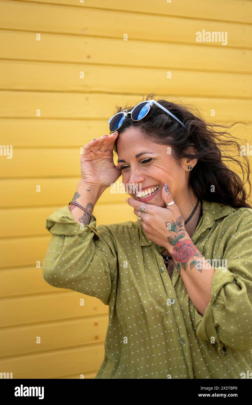 Donna sorridente in mezza età con tatuaggi e occhiali da sole Foto Stock