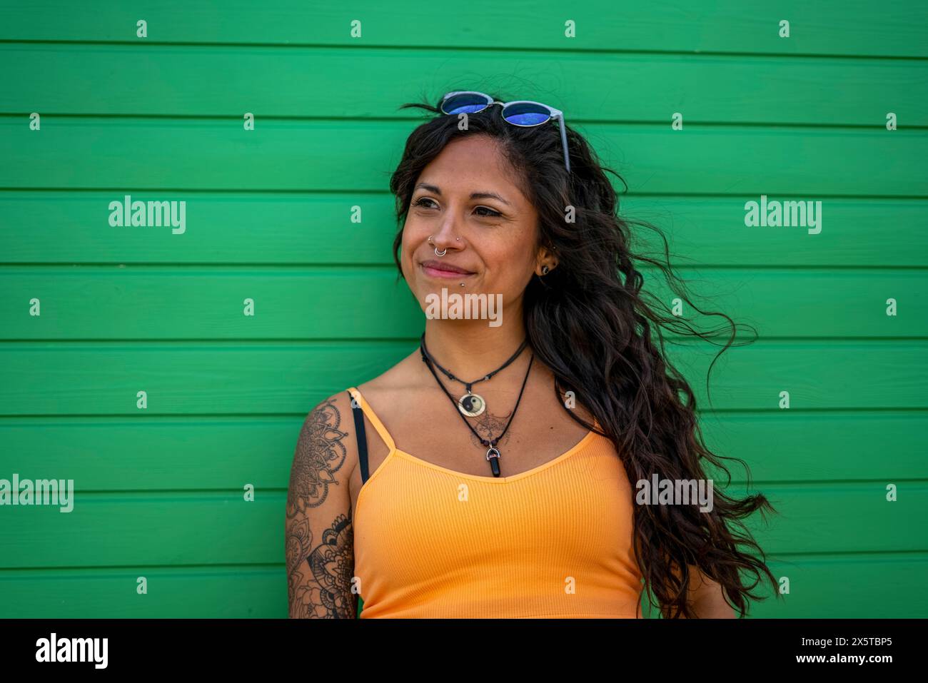 Donna sorridente in mezza età con tatuaggi e occhiali da sole Foto Stock