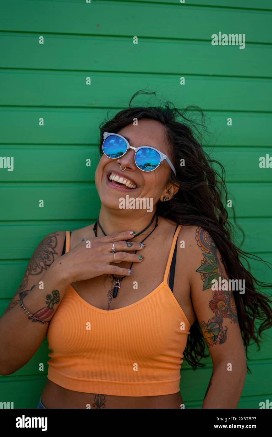 Donna sorridente in mezza età con tatuaggi e occhiali da sole Foto Stock