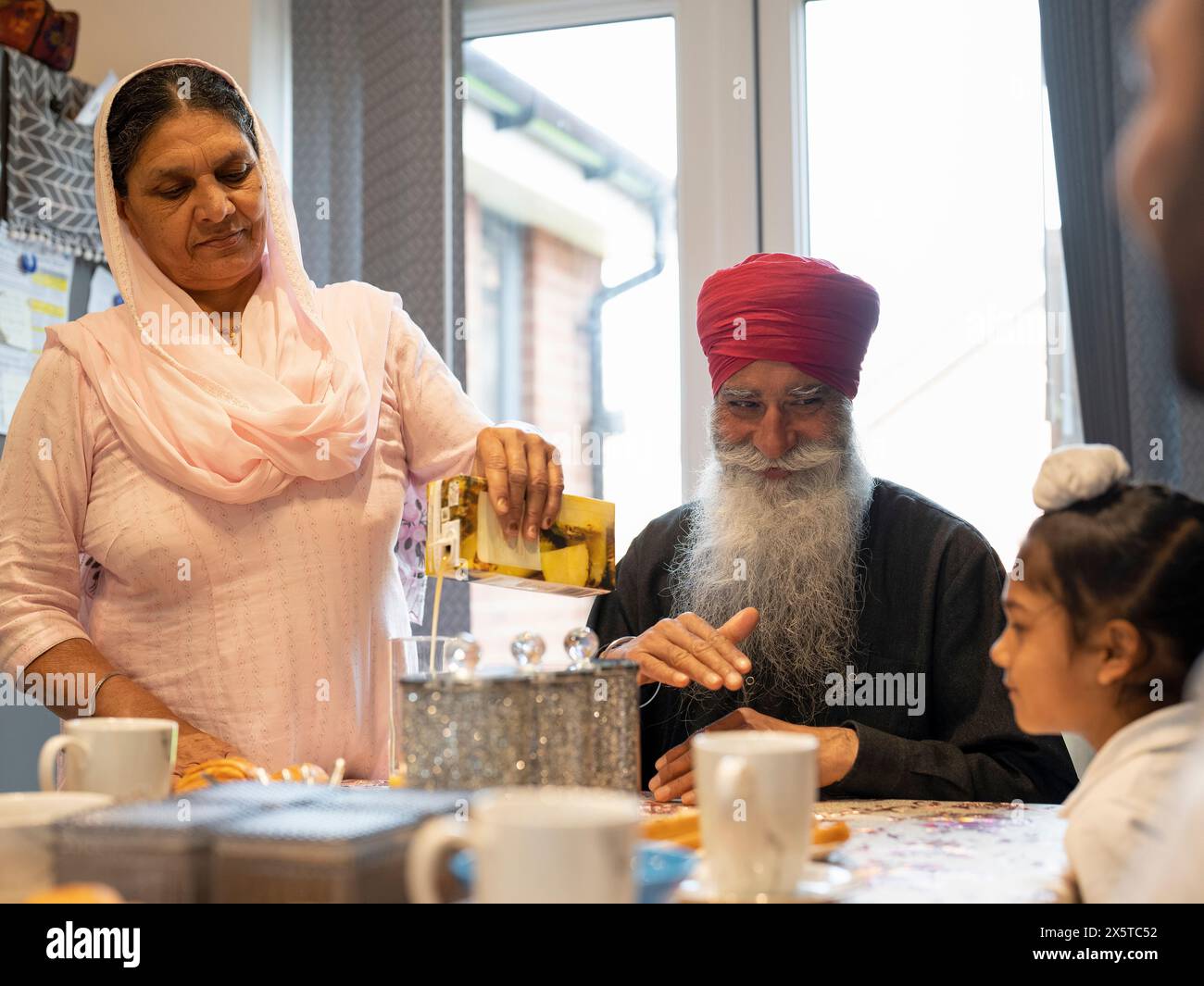 Nonni e nipoti (6-7) seduti a tavola a casa Foto Stock