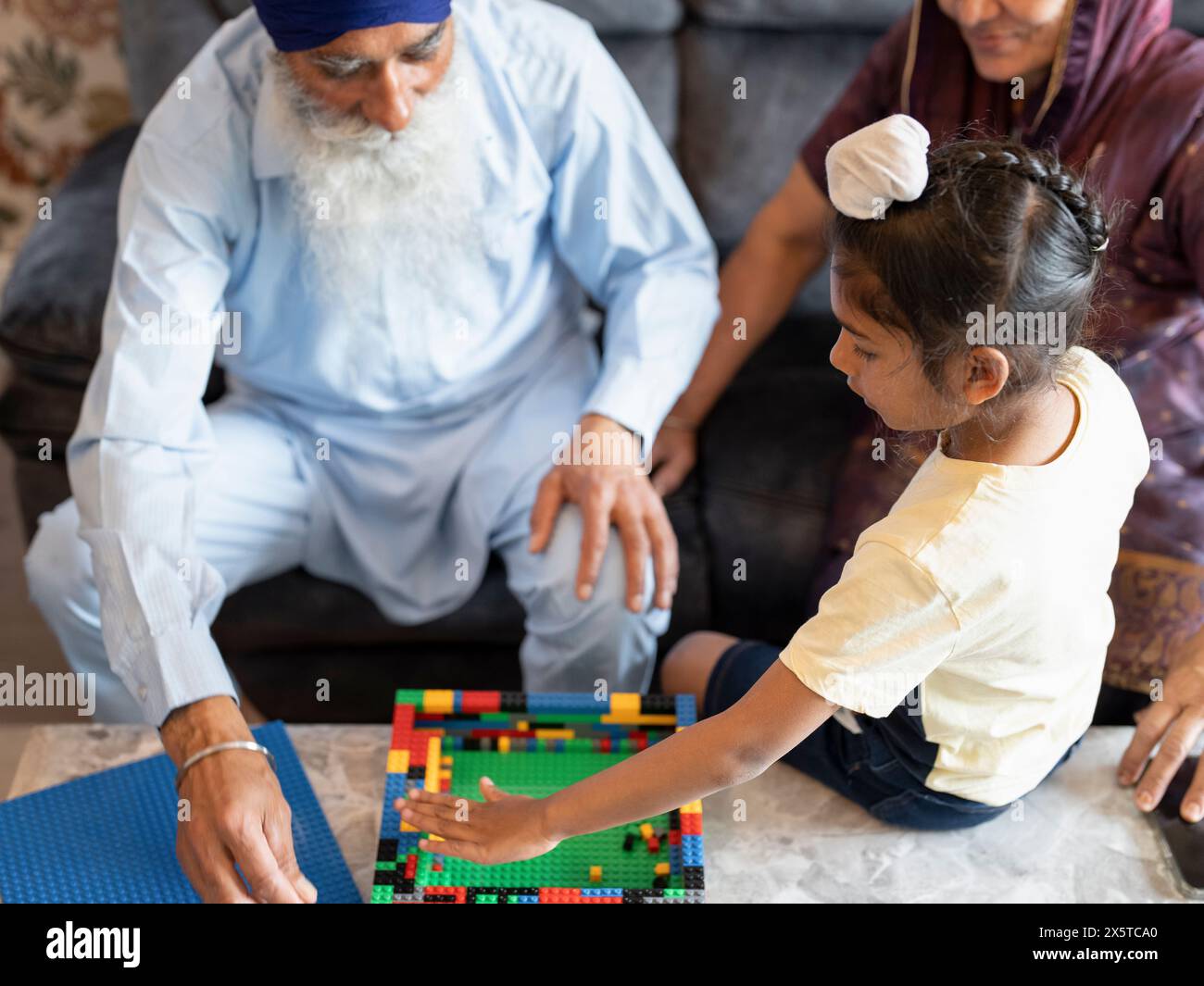 Nonni e nipote (6-7) che giocano con blocchi di giocattoli Foto Stock
