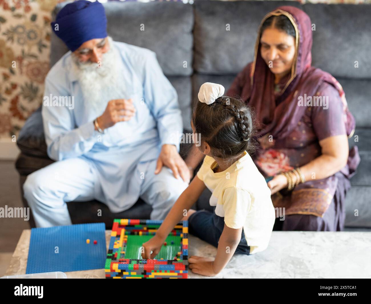 Nonni e nipote (6-7) che giocano con blocchi di giocattoli Foto Stock