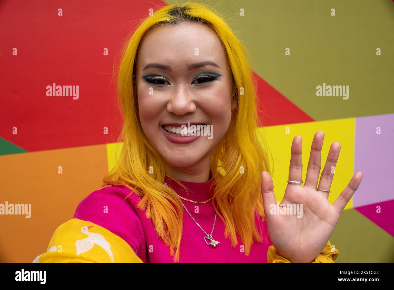 Ritratto di una giovane donna sorridente con capelli gialli che ondeggiano Foto Stock