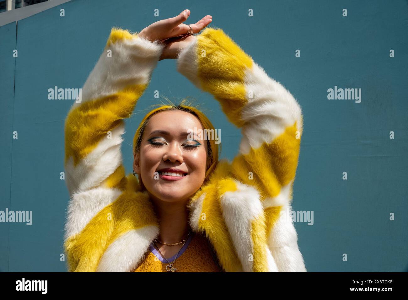 Giovane donna con i capelli gialli che tiene le braccia in alto Foto Stock