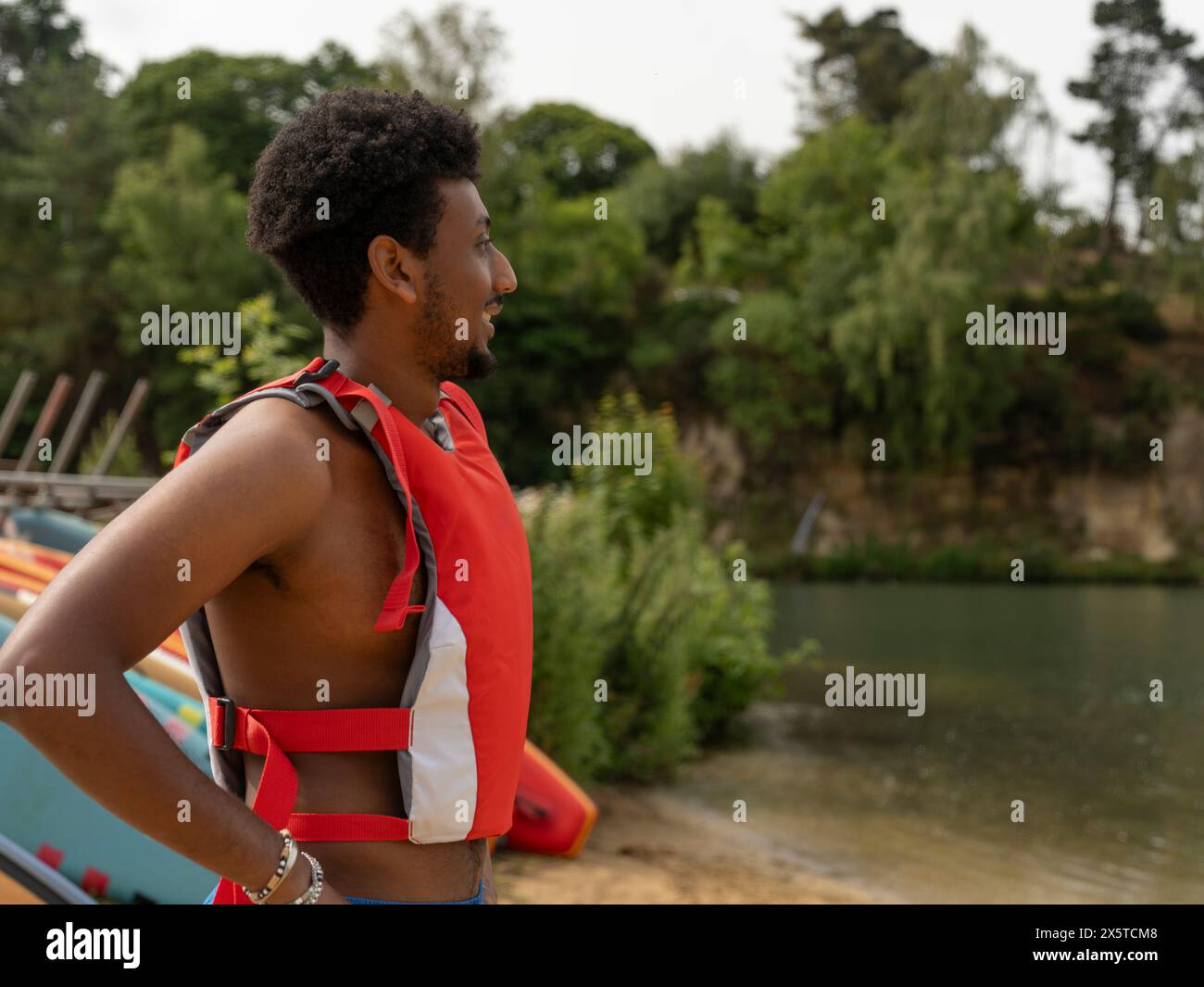 Ritratto di un uomo sorridente in un giubbotto salvagente che guarda il lago Foto Stock