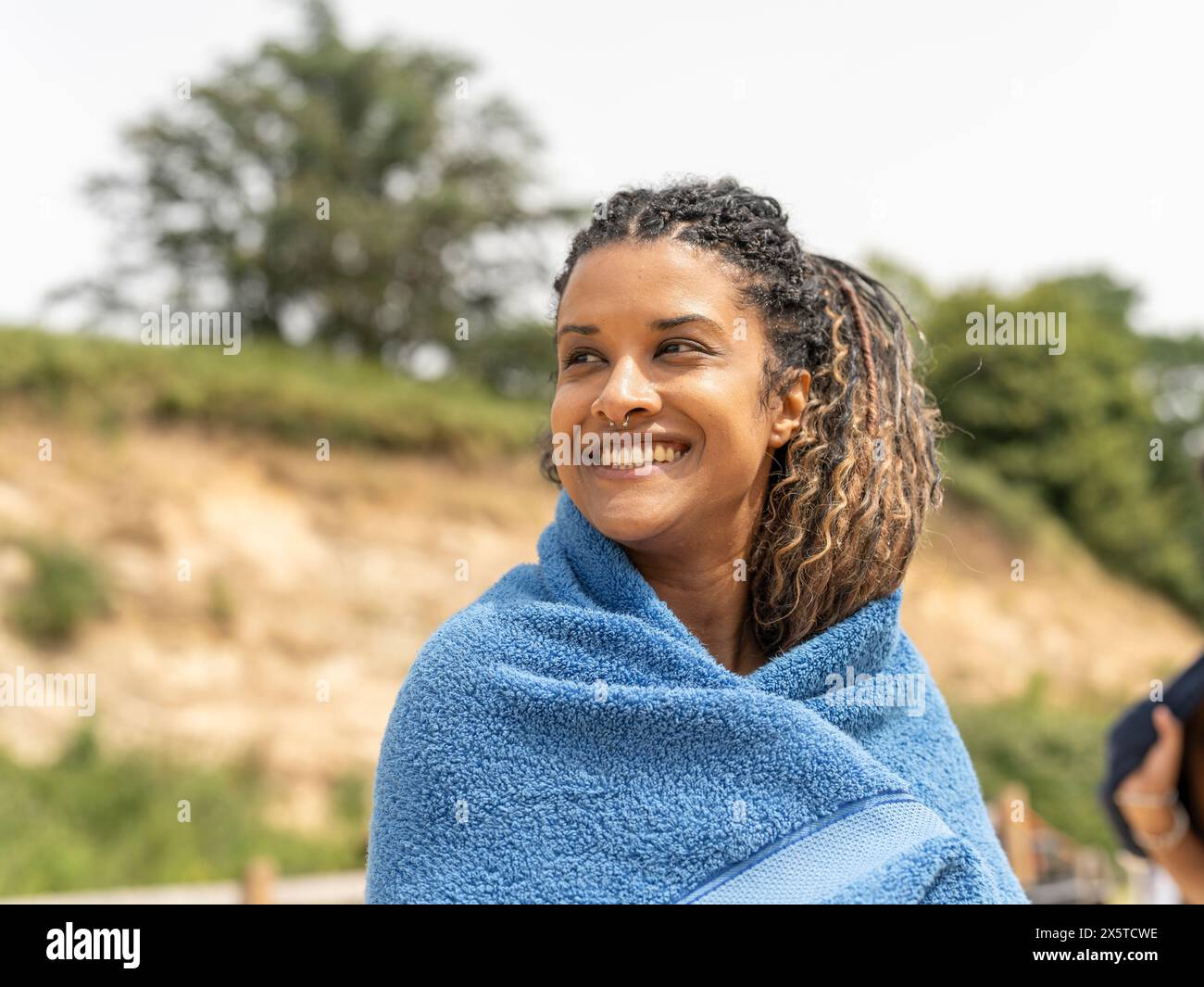 Ritratto di donna sorridente avvolto in asciugamano sulla spiaggia Foto Stock