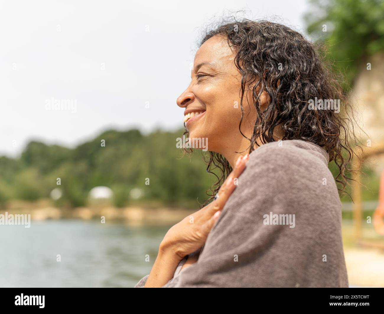Ritratto di donna sorridente avvolto in un asciugamano sul lago Foto Stock