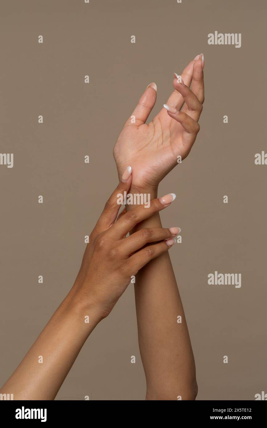 Scatto in studio di mani di donna su sfondo beige Foto Stock