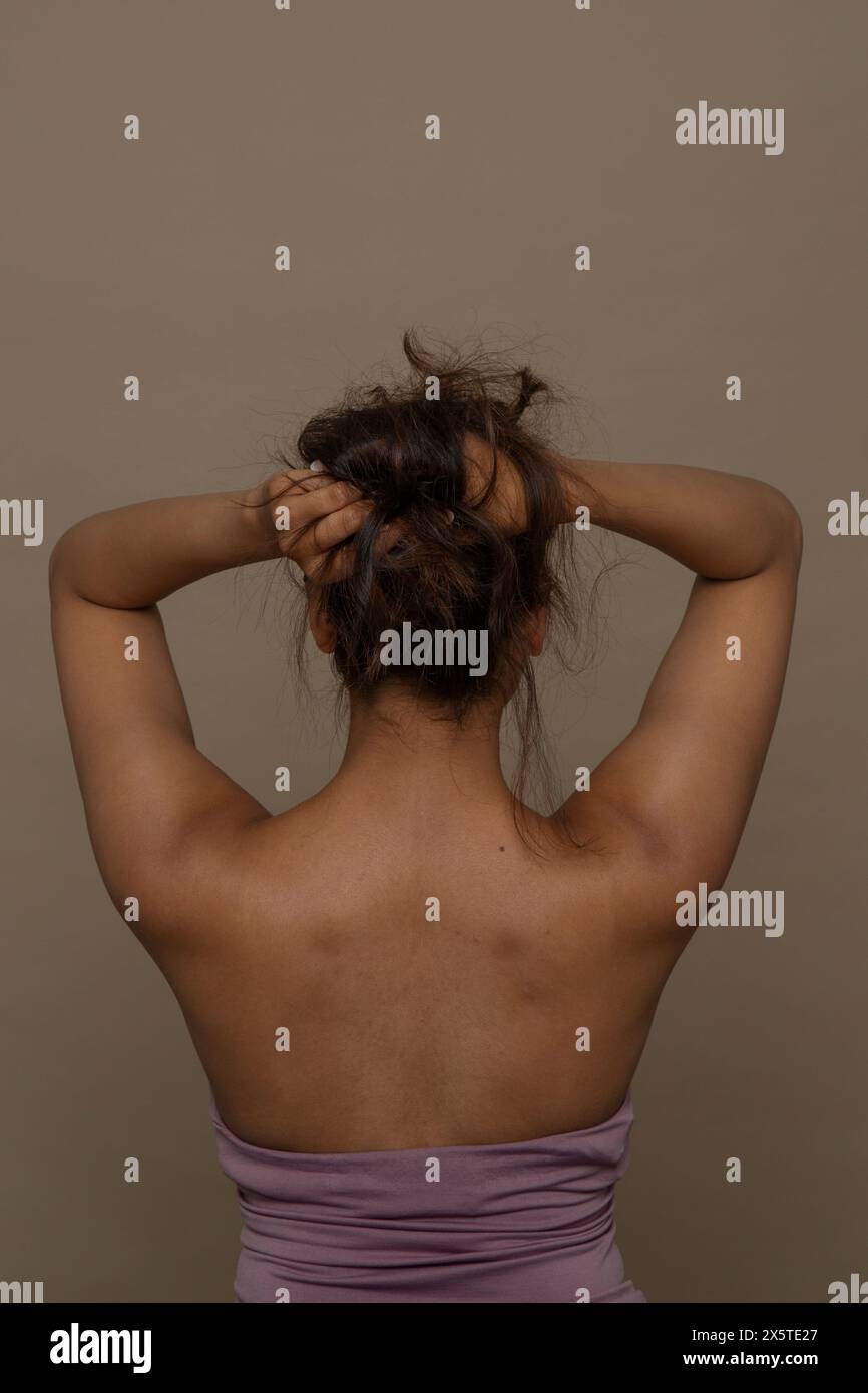 Vista posteriore della donna con le mani nei capelli Foto Stock