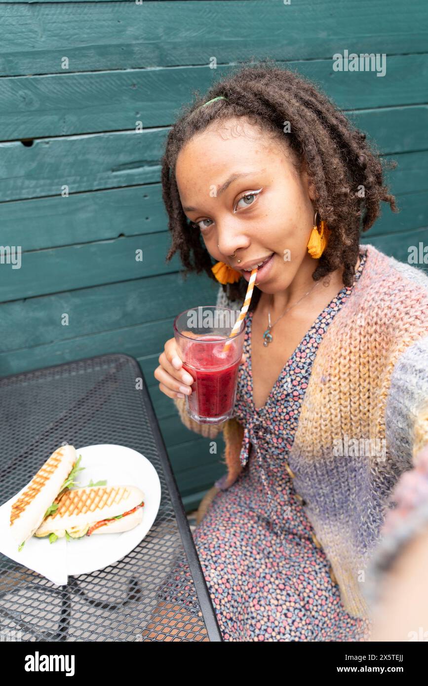 Ritratto di una donna sorridente che scatta un selfie durante la pausa pranzo in giardino Foto Stock