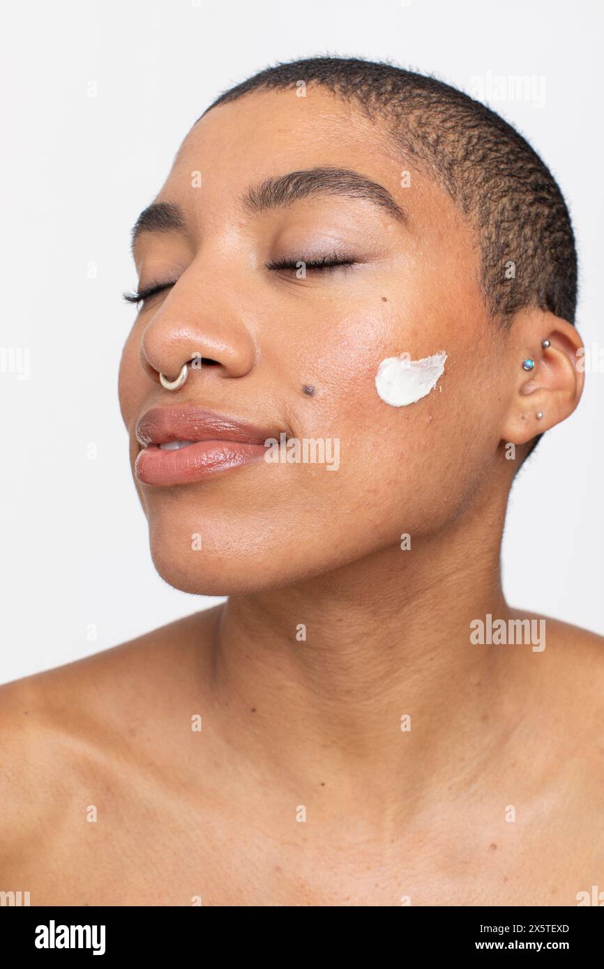 Ritratto in studio di una donna con crema per il viso sulla guancia Foto Stock