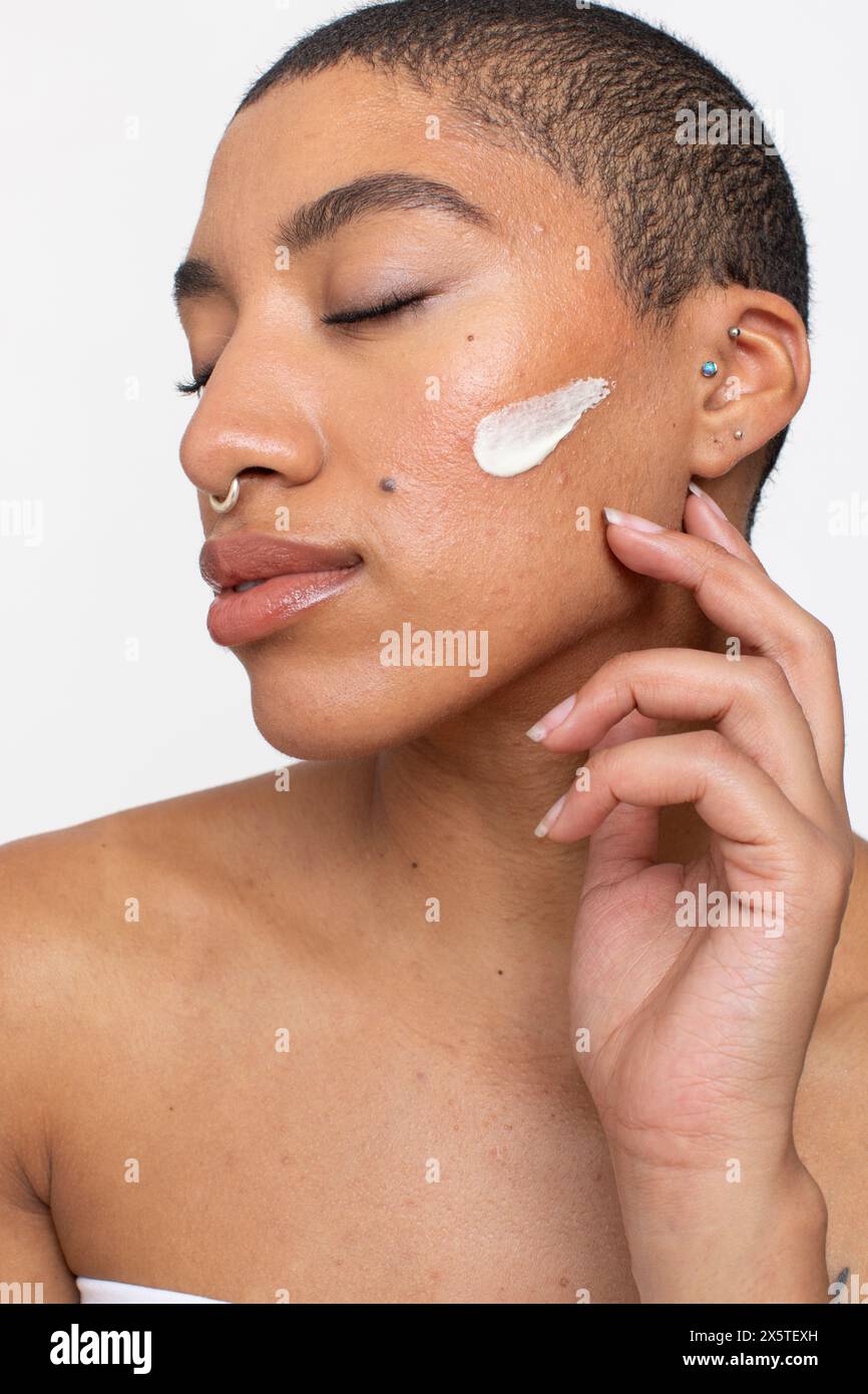 Ritratto in studio di una donna con la panna sulla guancia Foto Stock