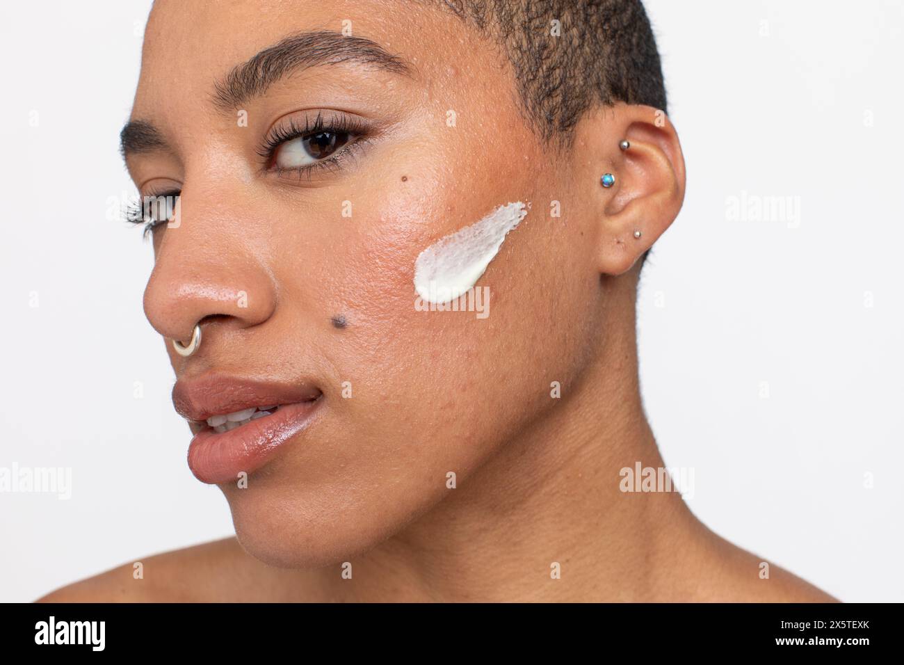 Ritratto in studio di una donna con la panna sulla guancia Foto Stock