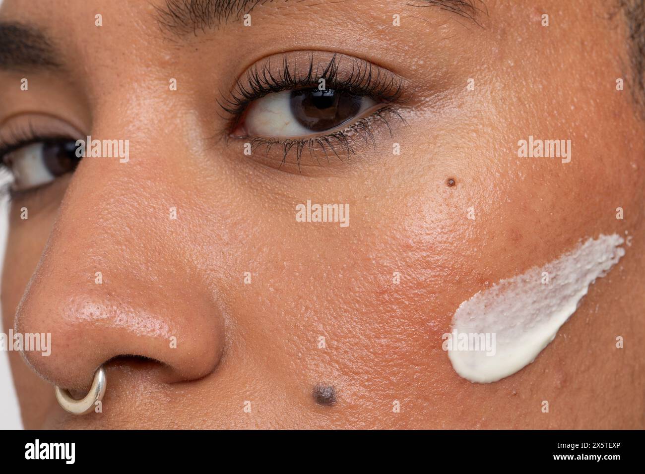 Primo piano di una donna crema per il viso sulla guancia Foto Stock