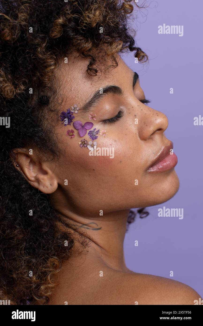 Donna con gli occhi chiusi e i fiori sul viso Foto Stock