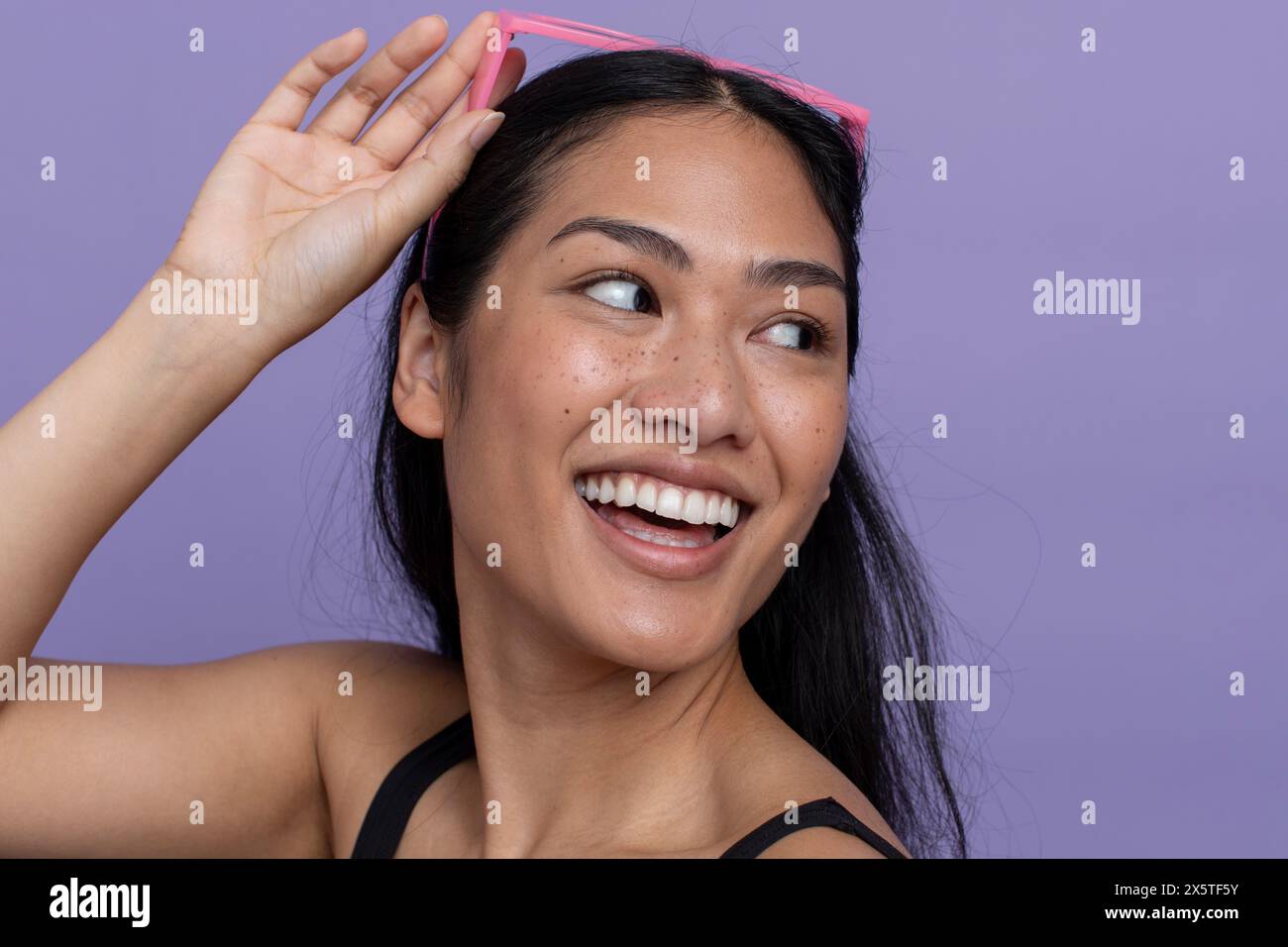 Donna sorridente con occhiali da sole sulla testa, che guarda a spalla Foto Stock