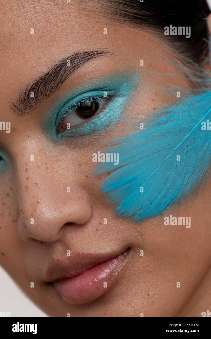 Ritratto di donna con trucco blu e piuma sul viso Foto Stock